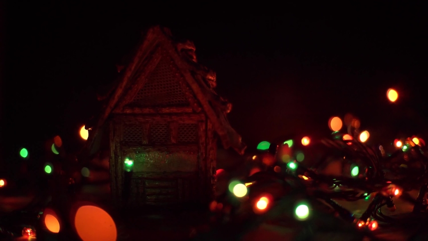 Merry Christmas and Happy New Year with toy house, garland glows.