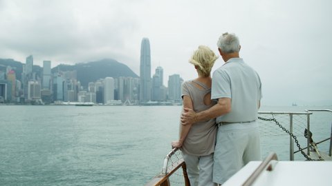 Hong Kong harbor skyline Victoria Peak viewed by anniversary retirement Caucasian couple on their round the world trip of a lifetime RED MONSTRO