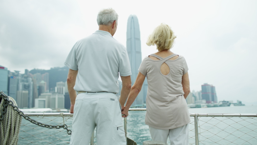 Hong Kong harbor skyline Victoria Peak viewed by anniversary retirement Caucasian couple on their round the world trip of a lifetime RED MONSTRO
