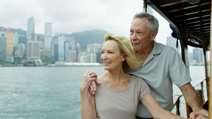 Retired senior Caucasian couple enjoying Hong Kong skyline Victoria Peak from Victoria harbor while celebrating an anniversary Asia RED MONSTRO