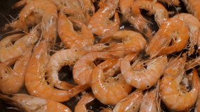 Shrimps are fried in a pan, steam is coming.
