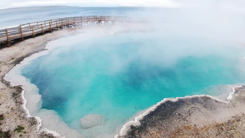 Traveler looks at Midway Geysers basin in Yellowstone National Park, view of Yellowstone lands, impressive nature shoots, steaming geysers, deep blue water, travel around USA on RV