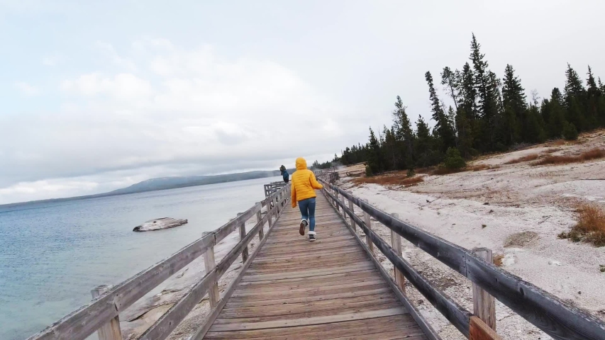 Travelers run around Midway Geysers basin in Yellowstone National Park, view of Yellowstone lands, impressive nature shoots, steaming geysers, deep blue water, travel around USA on RV