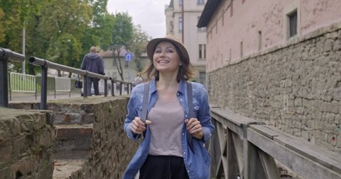 Smiling middle-aged woman walking in an old tourist town.