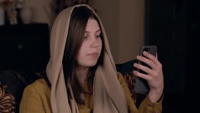 A young pretty Christian woman with a headscarf on her head, Caucasian in appearance, sits in an armchair and records a vlog video. Social Media Blogging Concept