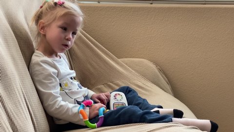 San Jose, CA - November 14, 2019: Toddler girl with lowest spectrum of autism rocking on a sofa. Normal behavior for kids with this stage of autism. 