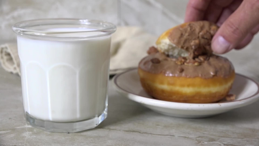 Dunking a donut in a glass of milk close up