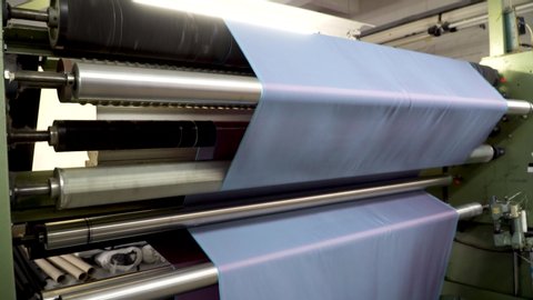 At a textile factory, checks the fabric roll on an automatic inspection machine. Examination of fabric for inspection and analysis before use for sewing clothes. 4k footage.