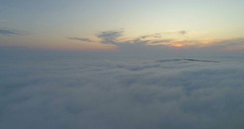 The sun is hidden behind the clouds at sunset fog. Drone flying over the clouds at sunset. 