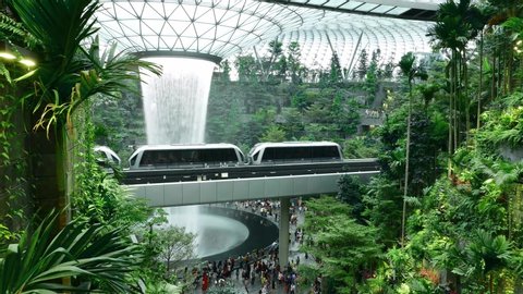 Singapore / Singapore - May 5 2019 : Waterfall inside glass dome at Jewel at Changi with train passing across