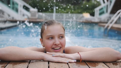 Portrait of a smiling teenage girl with dental plates at the edge of the pool, close-up.