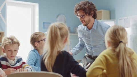 Enthusiastic Teacher Explains Lesson to a Classroom Full of Bright Diverse Children, Leads Class with Energetic Discussion. In Elementary School Group of Smart Multiethnic Kids Learn New Things
