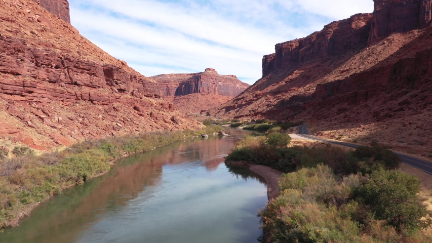 Drone flies over the Colorado river, which flows from a red rock massif of a brick structure in a canyon, is destroyed by soil erosion and precipitation. In western United States in Utah, aerial view Royalty-Free Stock Footage #1041041246