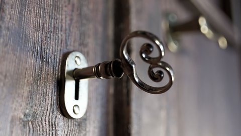 View at old-fashioned wooden doors focused on the golden lock door. A camera is moving and rotating around the center of key showing the whole object. High detailed materials of wood and gold.
