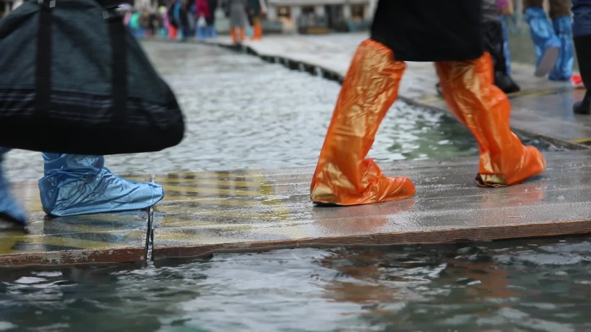 People with plastic gaiters or with boots on the walkway during the flood in Venice in Italy | Shutterstock HD Video #1041048020
