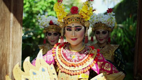Portrait view of beautiful Balinese females opening temple doors decorated in jewelled encrusted colorful costumes while performing a spiritual dance Indonesia travel and tourism RED MONSTRO