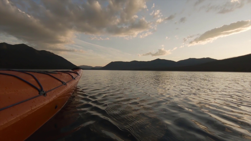 Kayaking in Glacier Lake surrounded by the beautiful Canadian Rocky Mountains during a cloudy summer sunset. Taken in Upper Waterton Lake, Alberta, Canada.