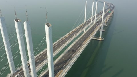 Tilting drone flight over tall section of the massive Jiaozhou Bay Bridge project, a modern highway spanning 25.9 kilometres connecting Qingdao with Huangdao in China