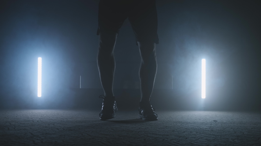 Legs of male boxer with skipping rope. Fighter doing jump rope exercises in dark gym with smoke in slow motion. Warming up and training of fighter. Close-up view in 4K, UHD Royalty-Free Stock Footage #1041050102