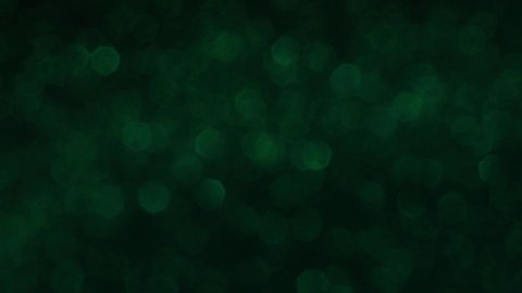 Seamlessly looping slowly spinning flickering green glitter bokeh particles on dark surface