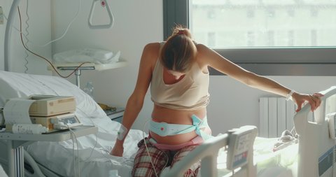 Authentic shot of an young pregnant woman is having contractions few hours before to give a birth to her future baby in a delivery room of a hospital.