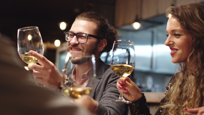 Best friends sitting in restaurant for dinner and making a toast with white wine. On table is food. Royalty-Free Stock Footage #1041058898