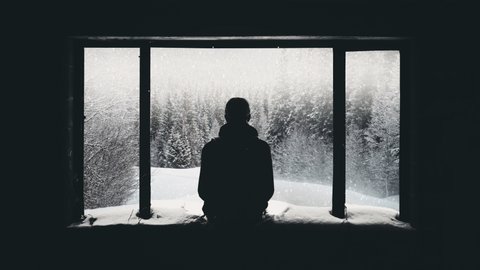 Meditating in the winter snow scene. Zen meditation concept.The relaxed man, looking towards the horizon.Peaceful snowy landscape in black and white. Snowing through the window. Travel stuff Tourism. 