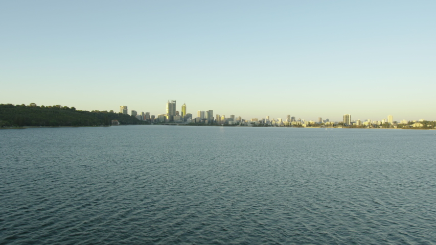 Aerial view travelling across Swan River at sunrise to Perth city skyline with Brookfield Place skyscraper Western Australia