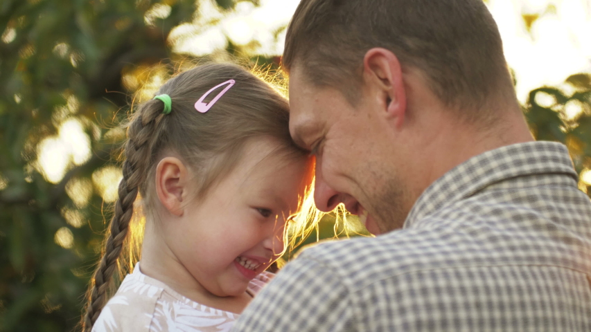 Portrait of father holding child girl in his hands and hugging each other outdoors. Dad cudding and kissing with his daughter. Father's day | Shutterstock HD Video #1041068828