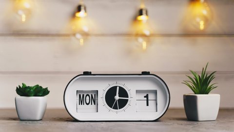 A white flip clock on table turns through month, flipping days and date, countdown from 1st to 31th