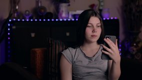 young happy caucasian woman using mobile phone for video chat online with friends and blogging for social media while sitting in room at cozy home.