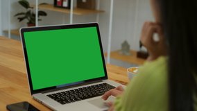 Over the shoulder shot of a business woman working in office interior on pc on desk, looking at green screen. Office person using laptop computer with laptop green screen, sitting at wooden table - Powered by Shutterstock - Get 15% off with code: PIKWIZARD15
