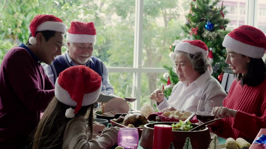 Asian family is eating for Thanksgiving. There are grandfathers, grandmothers, parents and daughter on the dinner table home. Celebrate Christmas and New Year. International family day. 4K Slow motion