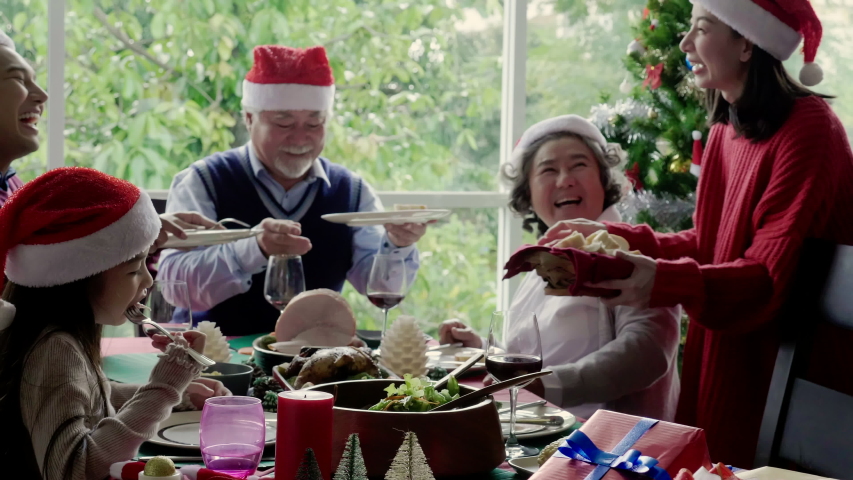Asian family is eating for Thanksgiving. There are grandfathers, grandmothers, parents and daughter on the dinner table home. Celebrate Christmas and New Year. International family day. 4K Slow motion