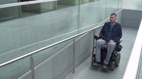4k resolution follow of a man with muscular dystrophy on electric wheelchair using a ramp. Accessibility concept