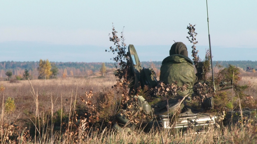 Soldier in full ammunition assesses the situation while sitting on Armored Personnel Carrier