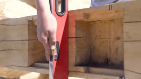 Close up of a carpenter hand installing construction level to the wooden beam. Clip. Process of wooden house building, professional equipment.