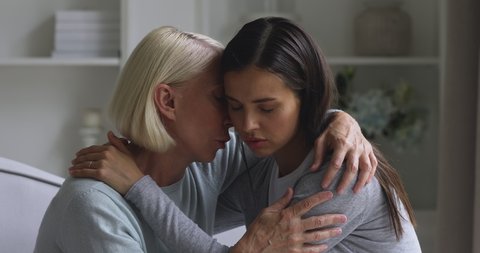 Worried mature mother comforting consoling or apologizing sad young daughter asking for forgiveness saying sorry, two age generation women hugging reconciling express support making peace concept