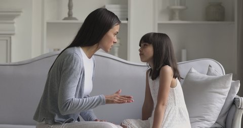 Angry young adult mother scolding stubborn difficult little child daughter at home, stressed annoyed frustrated mum nagging shouting at rebellious kid girl demand discipline telling reprimand concept