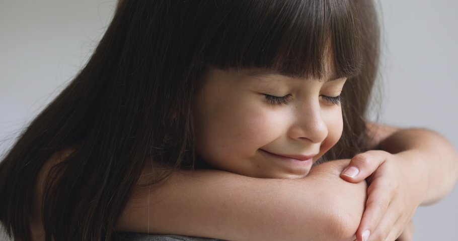 Happy cute affectionate adopted little kid girl hugging foster care parent mother with eyes closed, adorable small child daughter embrace mum cuddling enjoy tender sweet moment concept, close up view | Shutterstock HD Video #1041120067