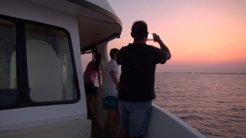 Larnaka, Cyprus - October 20 2019: Back view of adult man taking landscape sunset photo on smartphone from yacht in the sea. | Shutterstock HD Video #1041127432