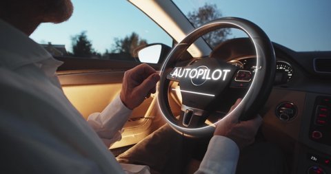 A man driving futuristic car activates autopilot on augmented reality hologram hud. Vehicle starts autonomous self-driving. Hands free system. Concept of Driverless Future Technology in transport.