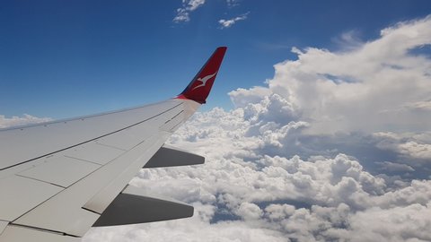 Sydney , NSW / Australia - 03 04 2019: Plane with Qantas Australia logo flying through fluffy white clouds.