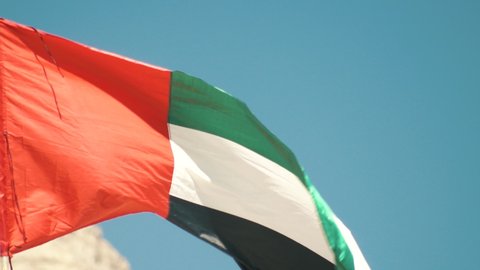 Flag of United Arab Emirates against blue sky in a summer day UAE flag waving in Dubai city , national symbol of UAE. blue sky, uae flag perfect for film, news, digital composition, uae flag day