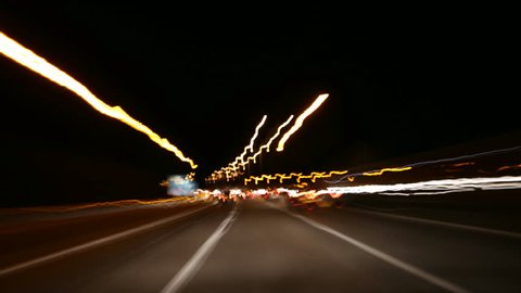 Stunning POV time lapse driving down a highway at night time. Lights blur and stream past at lightning speed