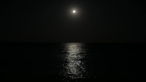 The full moon illuminates the water surface. Moon track on the surface of the water.