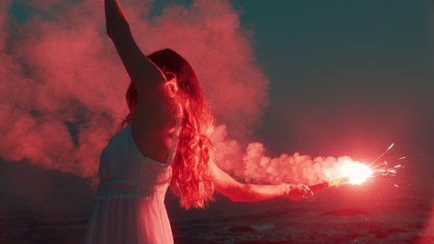 woman waving red flare dancing on beach at dawn expression creative freedom burning distress signal firework