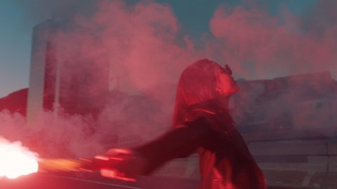 woman dancing with red flare in city at sunrise rebellious girl protesting in street with firework female millennial freedom movement