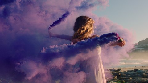 woman dancing with purple smoke bomb on beach celebrating creative expression with playful dance spin in slow motion