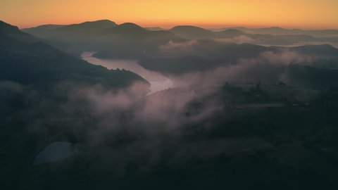 Dramatic sunrise over big river valley with clouds and fog